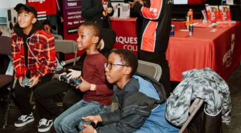 Kids playing video games intently at a NorQuest College event.