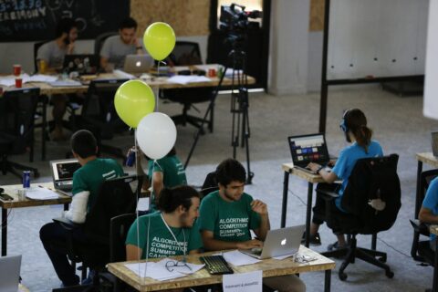 a group of people sitting at desks working on laptops