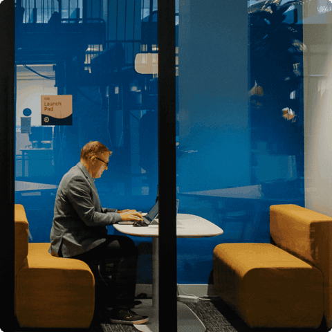 Man sitting in phone room, working on laptop at the Edmonton Unlimited space.